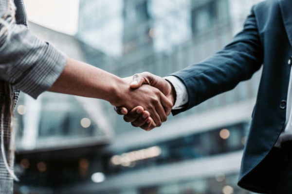 Meeting success. Two business persons shaking hands standing outside Meeting success